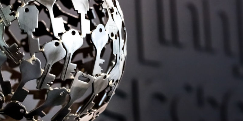 Close up of a decorative metal ball made up of keys in foreground. Blurry innspace logo in black on a black wall in reception area in background.
